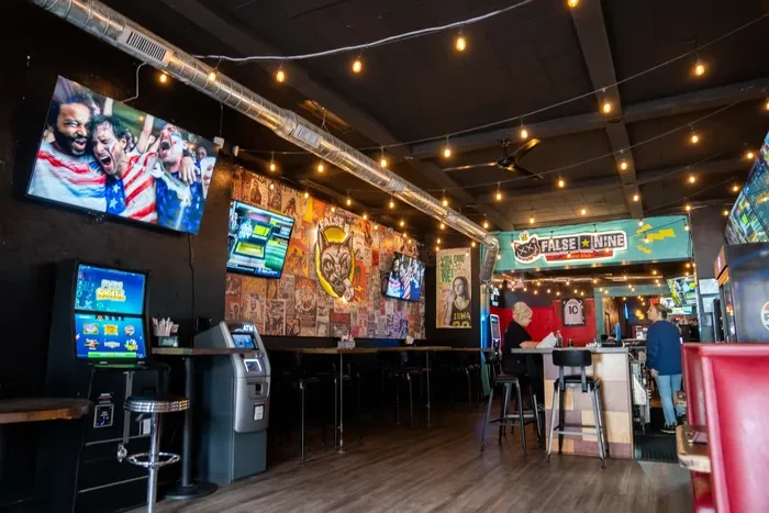 Inside False 9: string lights, music collage, bar seating and sport on the screens